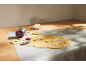Keksteig wird mit Ausstechformen auf einer Backmatte ausgestochen, mit Butter daneben.