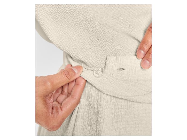 Nahaufnahme eines cremefarbenen, weichen Bademantels mit einem Knopf.