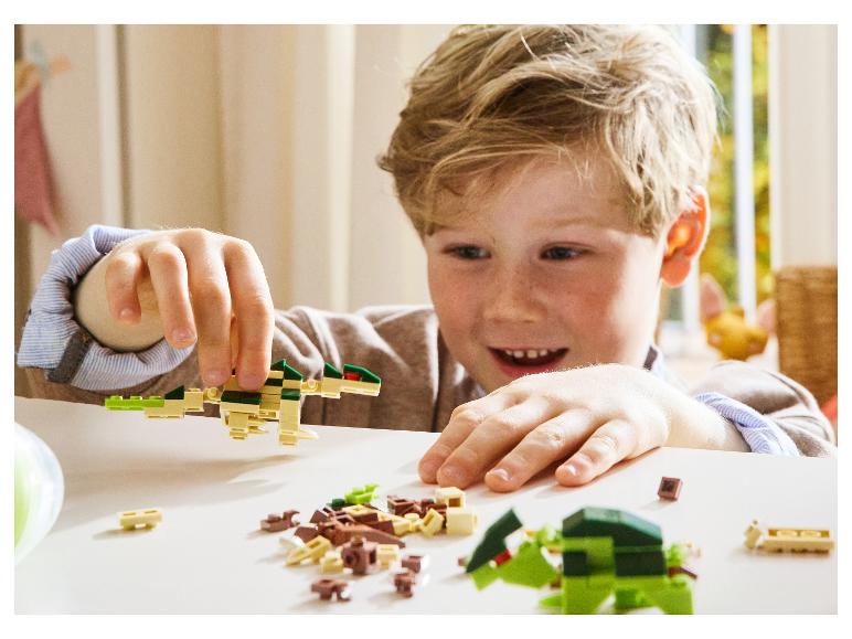 Ein lächelndes Kind spielt mit dinosaurierförmigem Konstruktionsspielzeug.