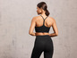 Eine Frau trägt einen schwarzen Sport-BH und Leggings.