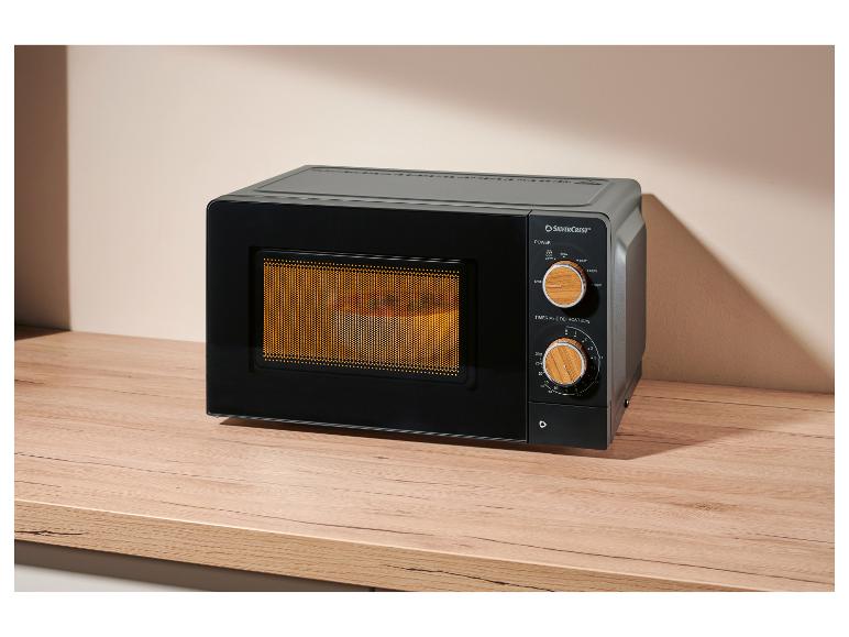 Schwarze Mikrowelle mit Holzknöpfen auf einer Holzarbeitsplatte.