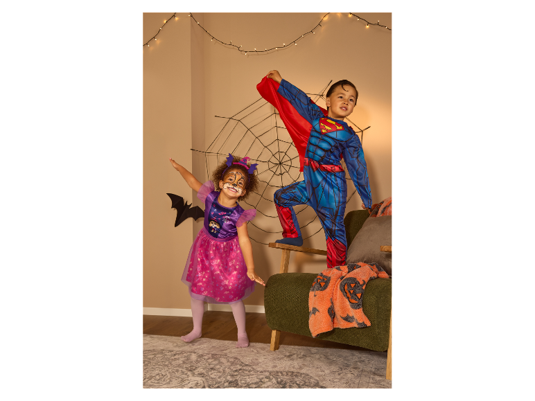 Kinder in Skye von Paw Patrol und Superman Kostümen feiern Halloween.