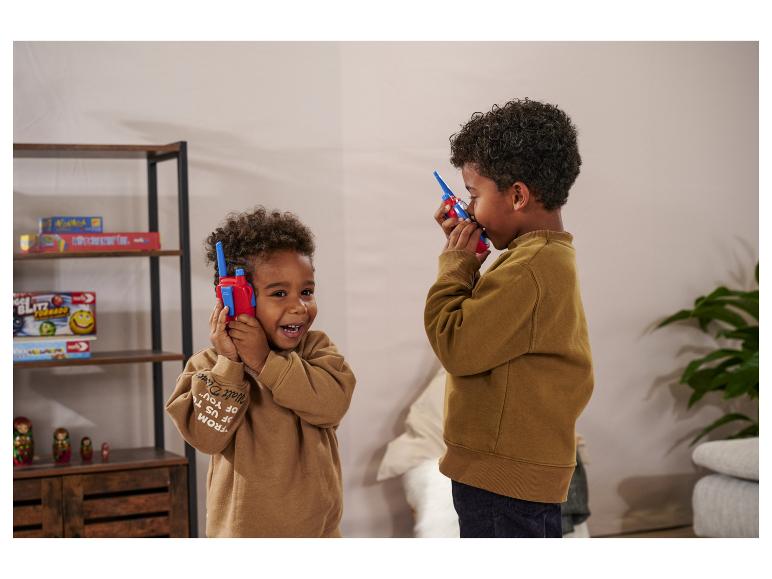 Zwei Jungen spielen mit roten und blauen Walkie-Talkies in einem Zimmer.