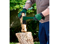 Person in grünen Handschuhen spaltet Holz mit einer grünen Axt auf einem Hackklotz.