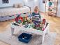 Junge spielt mit Holzeisenbahntisch mit Brücken und Gebäuden im Kinderzimmer.