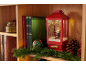Weihnachtslaterne mit Weihnachtsmannfigur, Büchern und Tannengirlande auf einem Holzregal.