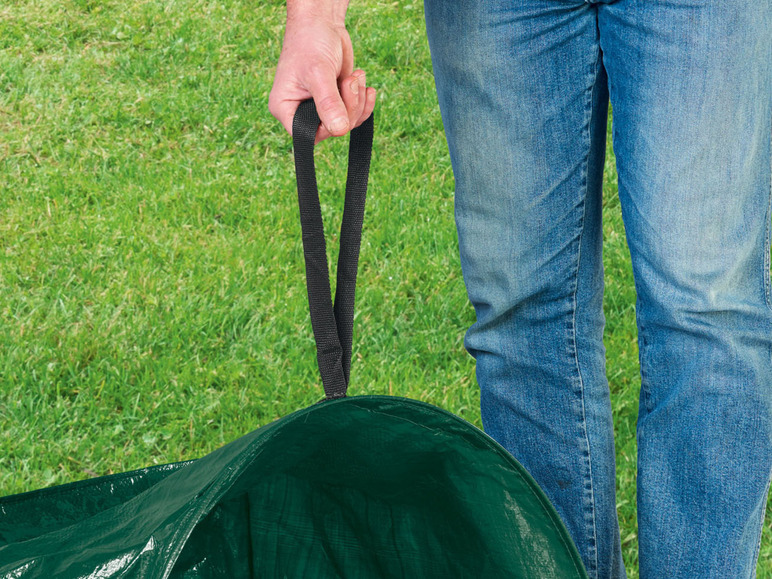 Eine Person hält einen grünen Gartensack.