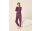 Lächelnde Frau in einem bequemen, violetten Hausanzug, bestehend aus Sweatshirt und Jogginghose.