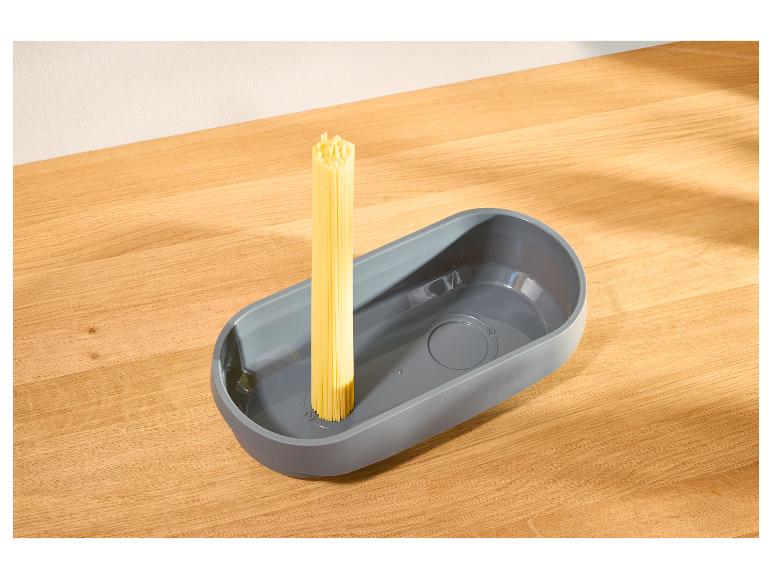 Grauer Nudelmesser mit rohen Spaghetti auf einem Holztisch.