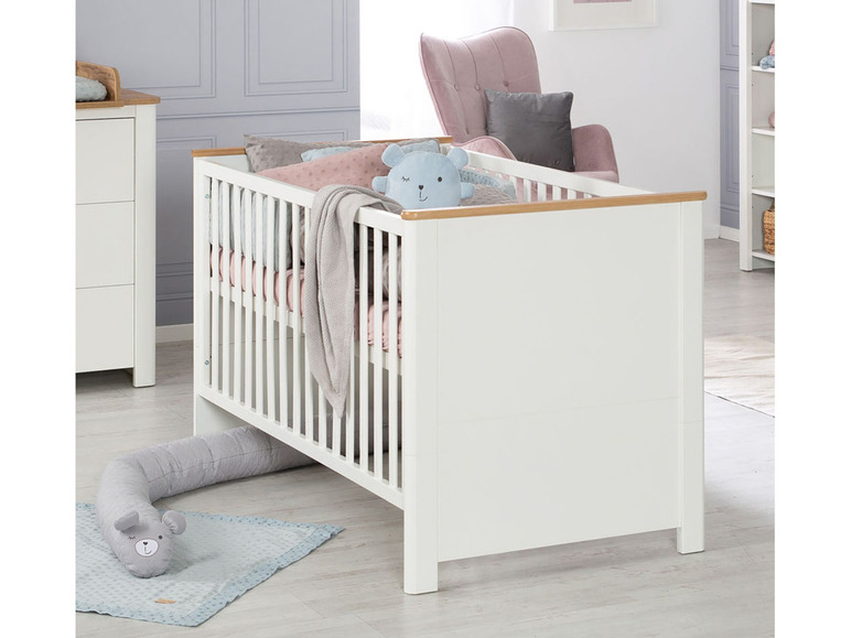 Ein weißes Babybett mit Holzdetails und einem grauen Plüschtier.