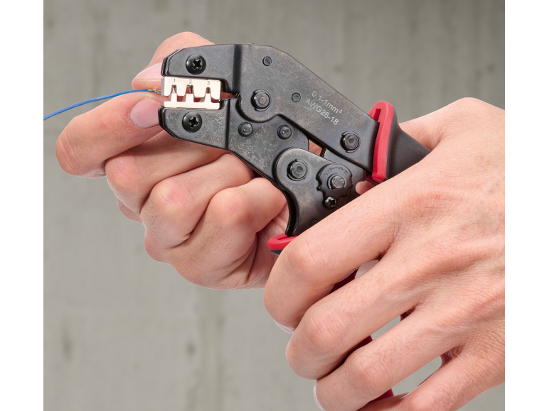 Hände verwenden eine Crimpzange zum Verbinden eines blauen Drahtes, mit 0.1-1mm² AWG26-18 Angaben.