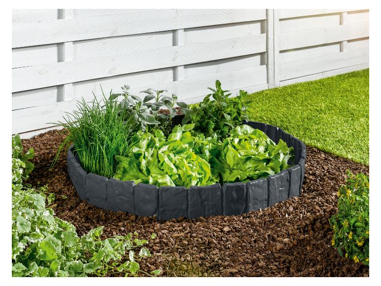 Ein Kunststoff-Gartenrand umgibt ein Beet mit Salat, Kräutern und Mulch.