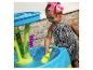 Glückliches Kind spielt mit einem Wassertisch und einer grünen Schaufel.