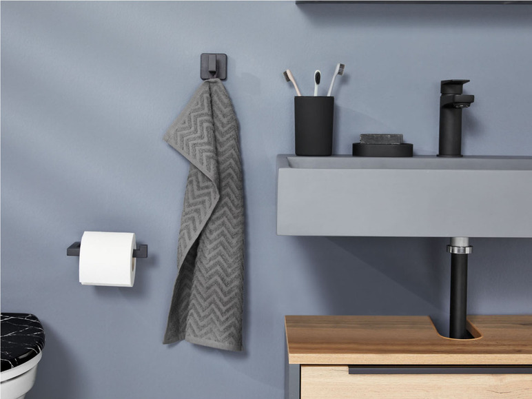 Ein Handtuchhalter, ein Toilettenpapierhalter und ein Waschbecken in einem Badezimmer.