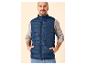 Mann in blauer Steppweste und grauem Pullover, Hände in den Taschen.