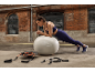 Eine Frau macht Unterarmstütz auf einem Gymnastikball, im Vordergrund liegen Fitnessbänder.