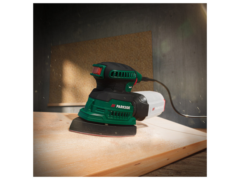 Eine grüne Parkside Schleifmaschine schleift eine Holzoberfläche.