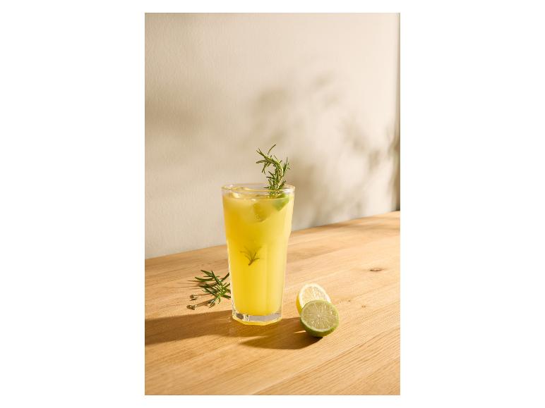 Glas Limonade mit Rosmarin und Limette auf einem Holztisch.
