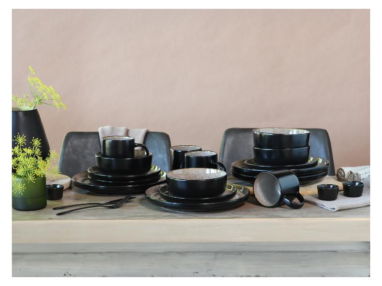 Schwarz-graues Geschirrset auf einem Holztisch mit Blumendekorationen.