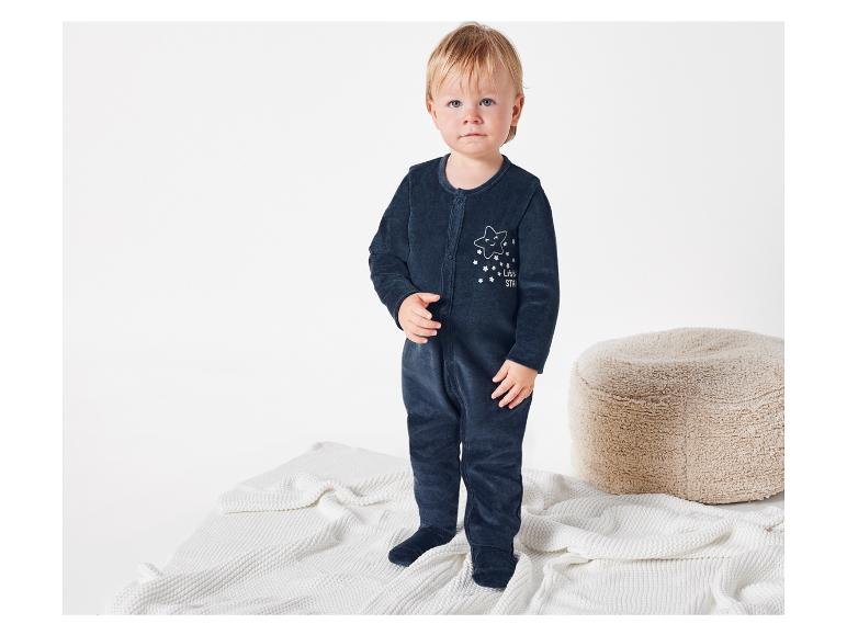 Baby in einem dunkelblauen Strampler mit Sternmotiv.