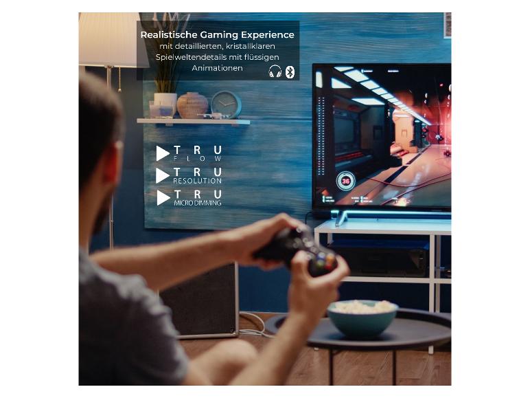 Ein Mann spielt ein Videospiel auf einem Fernseher mit TruFlow, TruResolution und TruMicro Dimming.