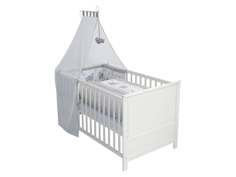 Ein weißes Babybett mit einem Moskitonetz und Bettwäsche mit Elefanten.