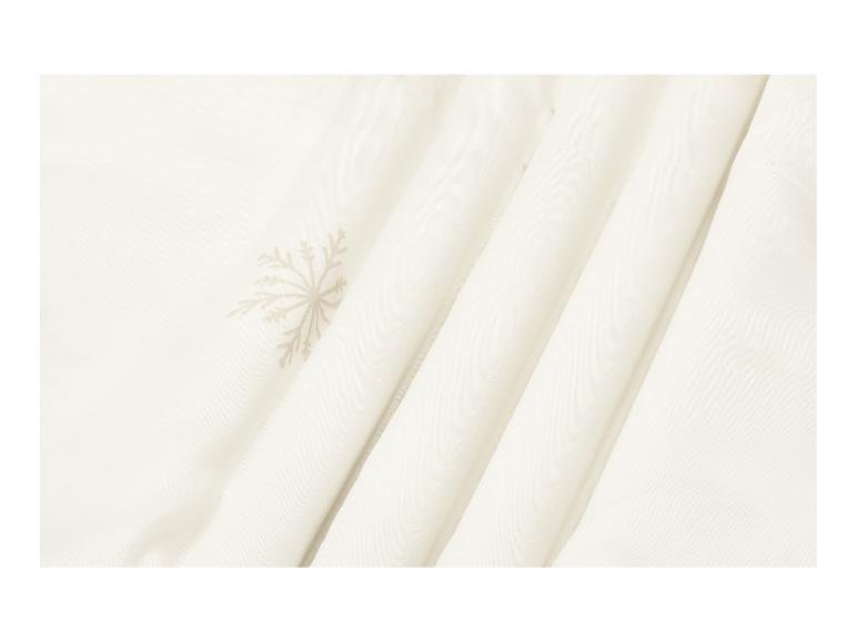 Cremefarbener Stoff mit dezentem Schneeflockenmuster und weichen Falten.