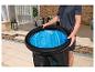 Person hält ein tragbares Eisbad mit blauer Innenverkleidung, draußen auf einer Terrasse.