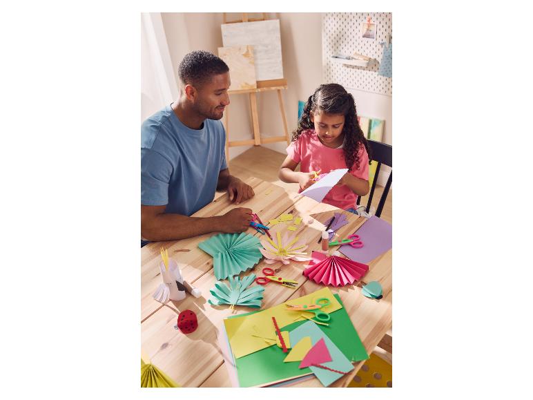 Vater und Tochter basteln bunte Papierdekorationen mit CRELANDO® Papierblöcken.