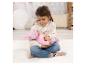 Junges Mädchen sitzt auf einem weißen Teppich und hält eine rosa gekleidete Babypuppe.