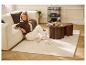 Frau sitzt auf Teppich neben Sofa, mit LIVARNO® LED-Akku-Tischleuchte und Couchtischen.