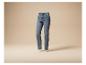 Blaue, ausgewaschene Damenjeans, schwebend vor beigem Hintergrund.