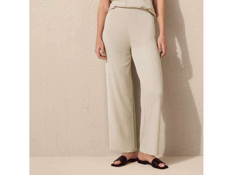 Beige, weite Hose mit schwarzen Sandalen.