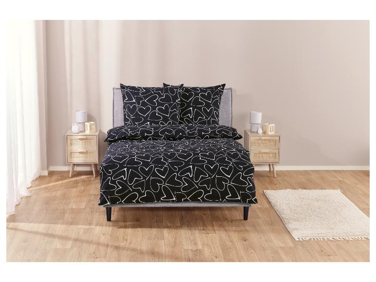 Eine schwarze Bettdecke mit weißen Herzen.