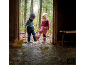Zwei Kinder in warmer Outdoor-Kleidung und Gummistiefeln spielen in einer Pfütze.