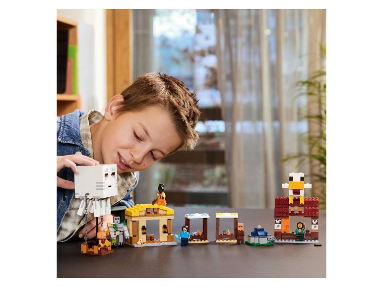Ein Junge spielt mit LEGO Minecraft Sets, darunter ein Eisengolem und ein Dorf.
