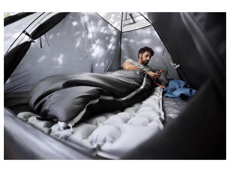 Mann in einem Zelt, der ein Smartphone in einem CRIVIT Schlafsack benutzt.