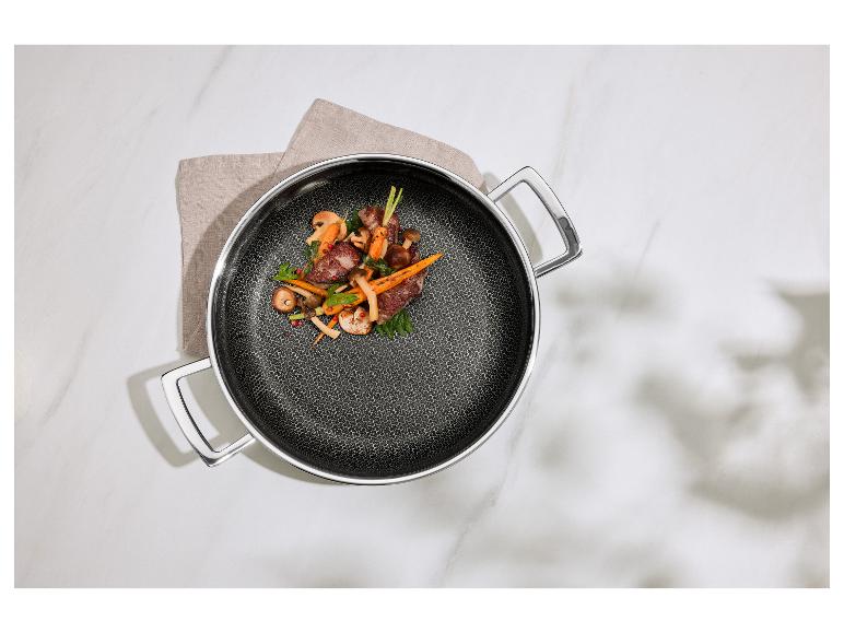 Bratpfanne mit Fleisch, Pilzen und Karotten auf einem Küchentuch auf einem Marmortisch