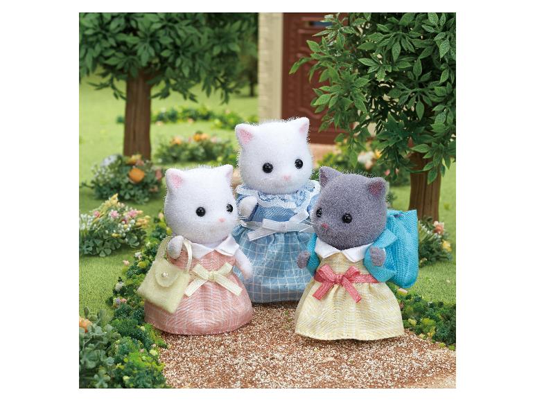 Drei Sylvanian Families Katzenfiguren in Kleidern auf einem Gartenweg.
