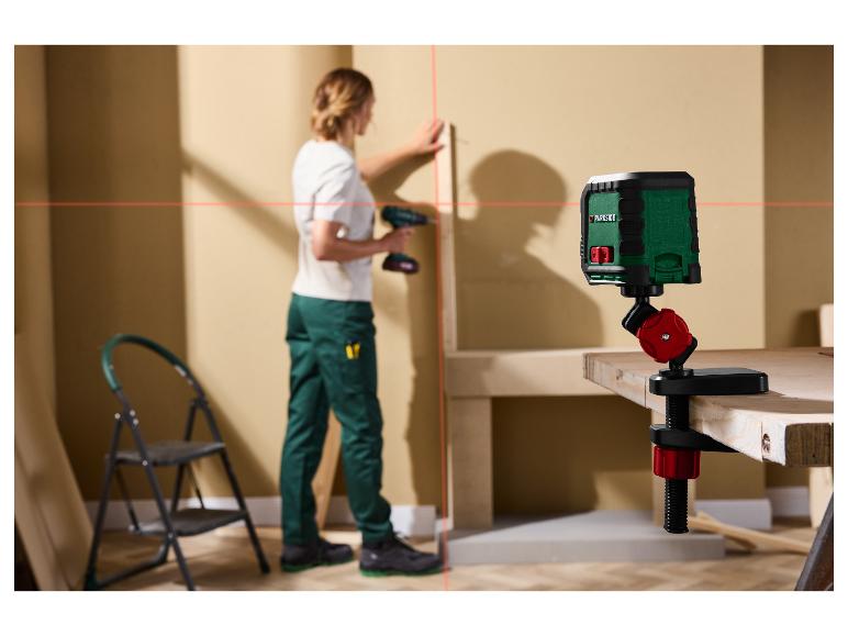 Ein Parkside Laser-Nivelliergerät projiziert rote Linien an eine Wand, während eine Person arbeitet.