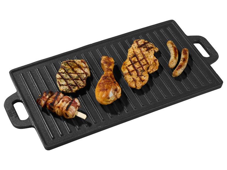 Gegrilltes Hähnchen, Würstchen und Speckspieße auf einer Gusseisen-Grillplatte.
