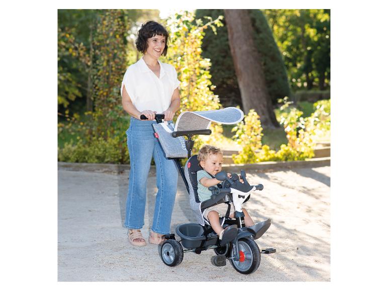 Kind auf einem Smoby Baby Drive Dreirad im Park.