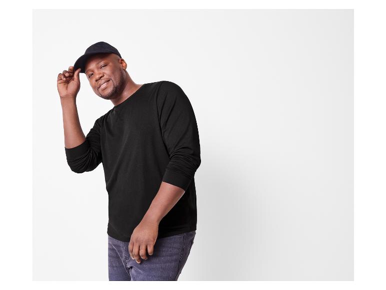 Lächelnder Mann in einem schwarzen Langarmshirt und schwarzer Kappe.