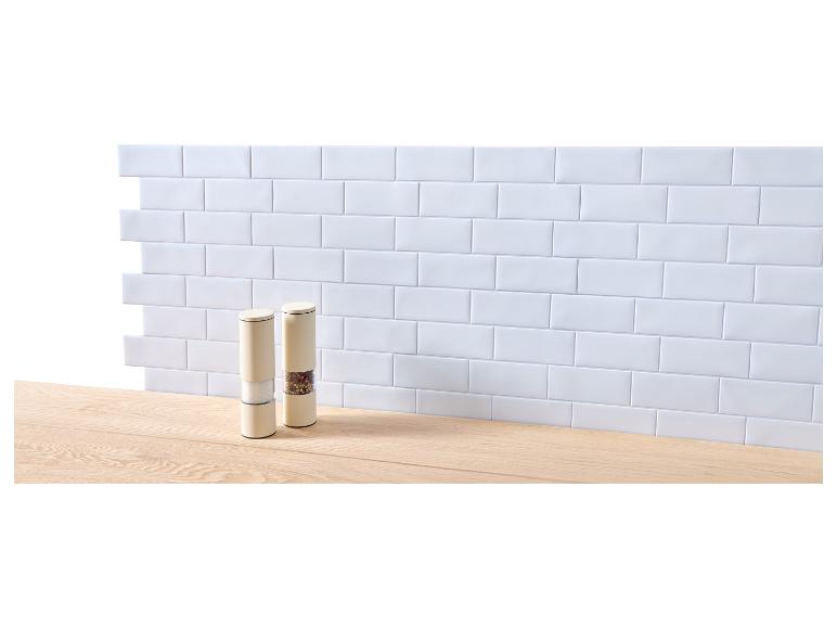 Zwei Salz- und Pfeffermühlen auf einer Holztheke vor einer weißen Fliesenwand.