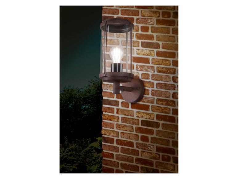 Außenwandleuchte mit klarem Glaszylinder und sichtbarer Glühbirne, an einer Ziegelwand montiert.
