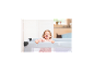 Lachendes Baby spielt in einem grauen Reisebett.
