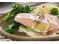 Lachs mit Brokkoli, Kartoffeln, Zitrone und cremiger Soße auf einem Teller.