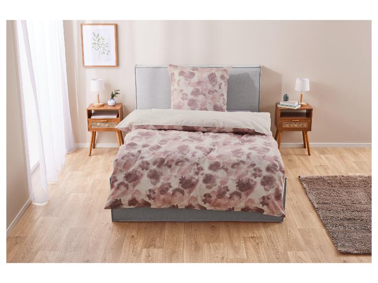 Bettenwäsche mit rosafarbenem Aquarellmuster auf einem modernen Bett.