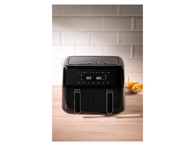 Eine moderne, schwarze Heißluftfritteuse auf einer Holztheke.