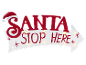 Weißes pfeilförmiges Schild mit rotem Text „SANTA STOP HERE“ und Weihnachtsmütze, beleuchtet.
